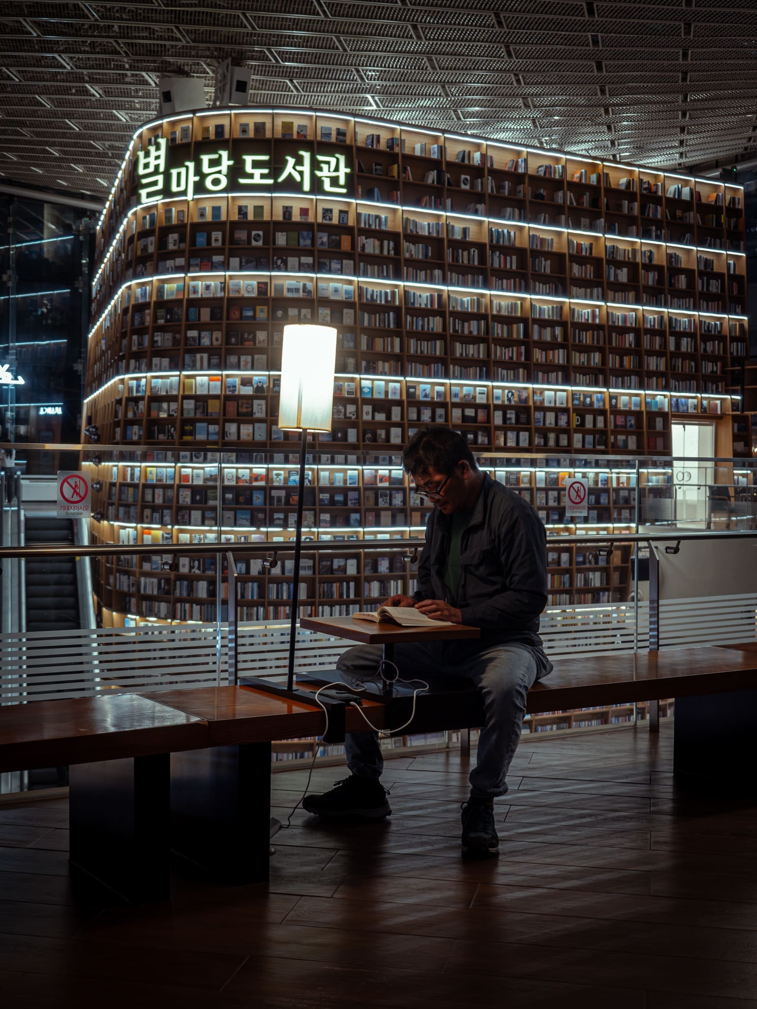 homme lisant assit sur un banc dans une bibliothèque à Séoul
